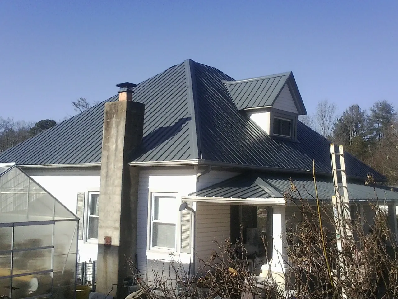 Dark blue standing seam metal roof on a white farmhouse with dormer — Slate & Tile Roof Repair by Roofing Brothers in Payette