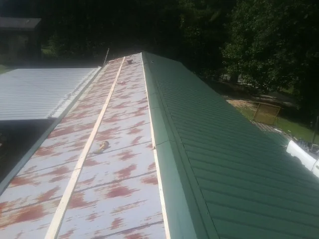 Old rusted panels beside newly installed green metal roofing — Wind Damage Roof Repair by Roofing Brothers in Payette