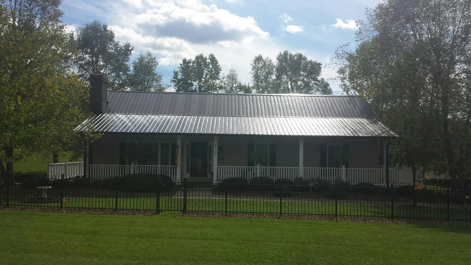 Gray metal roof on a brick ranch with a full width front porch — Gutter Guard Installation work by our crew in Payette