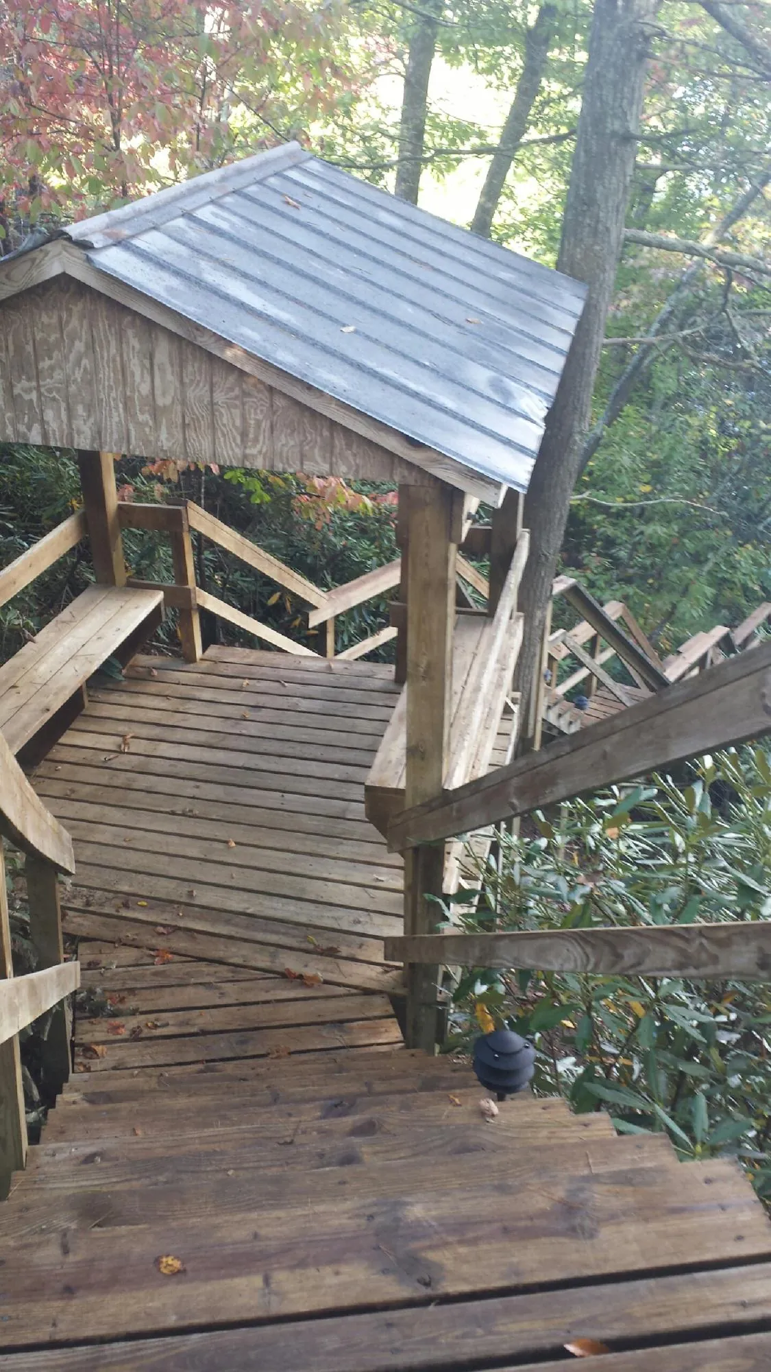Metal roofed shelter over wooden steps on a wooded walkway — Skylight Repair & Installation work by our crew in Payette