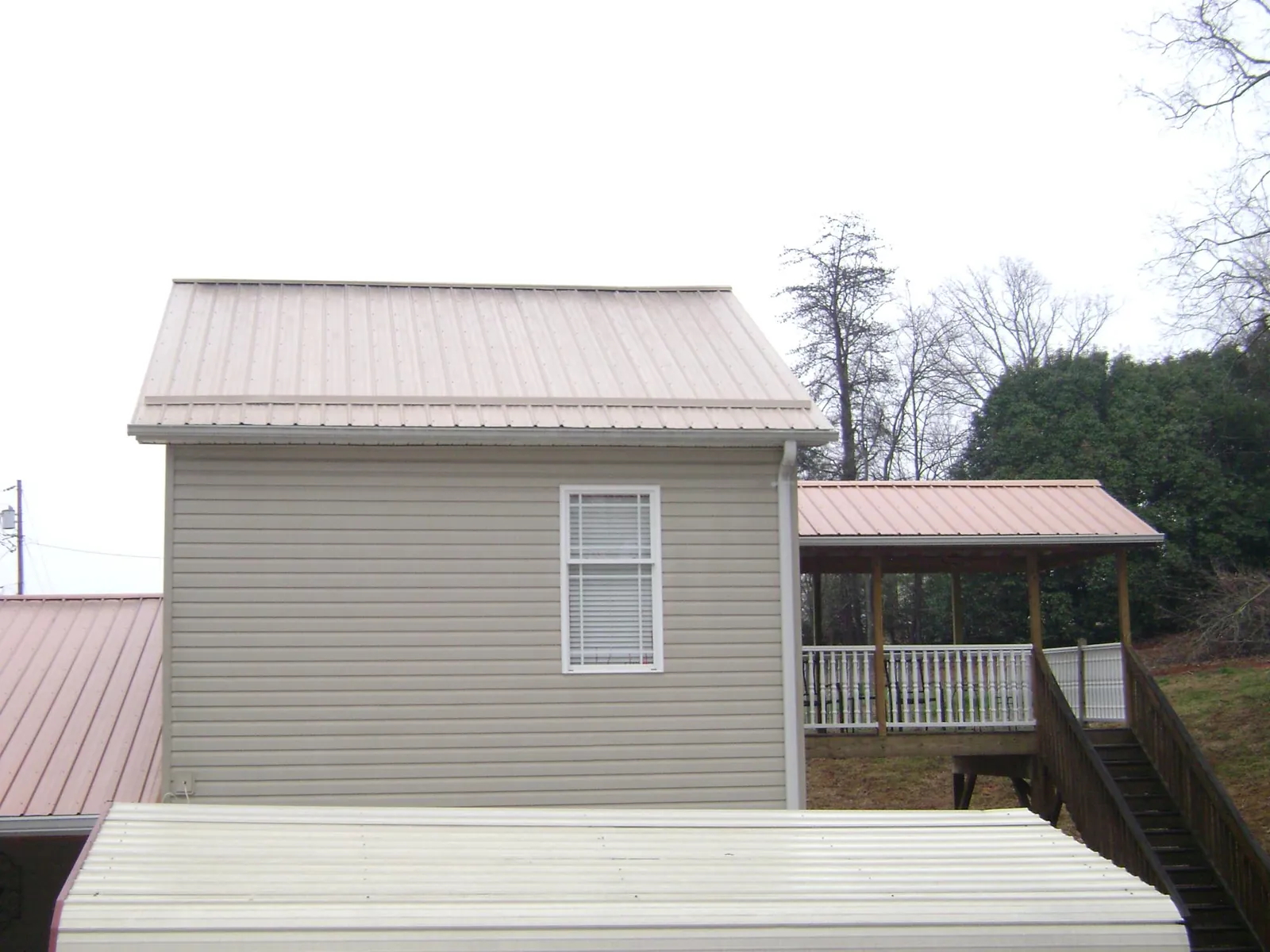 Tan metal roofs on a two story addition and attached porch, from a Roof Replacement job in Payette