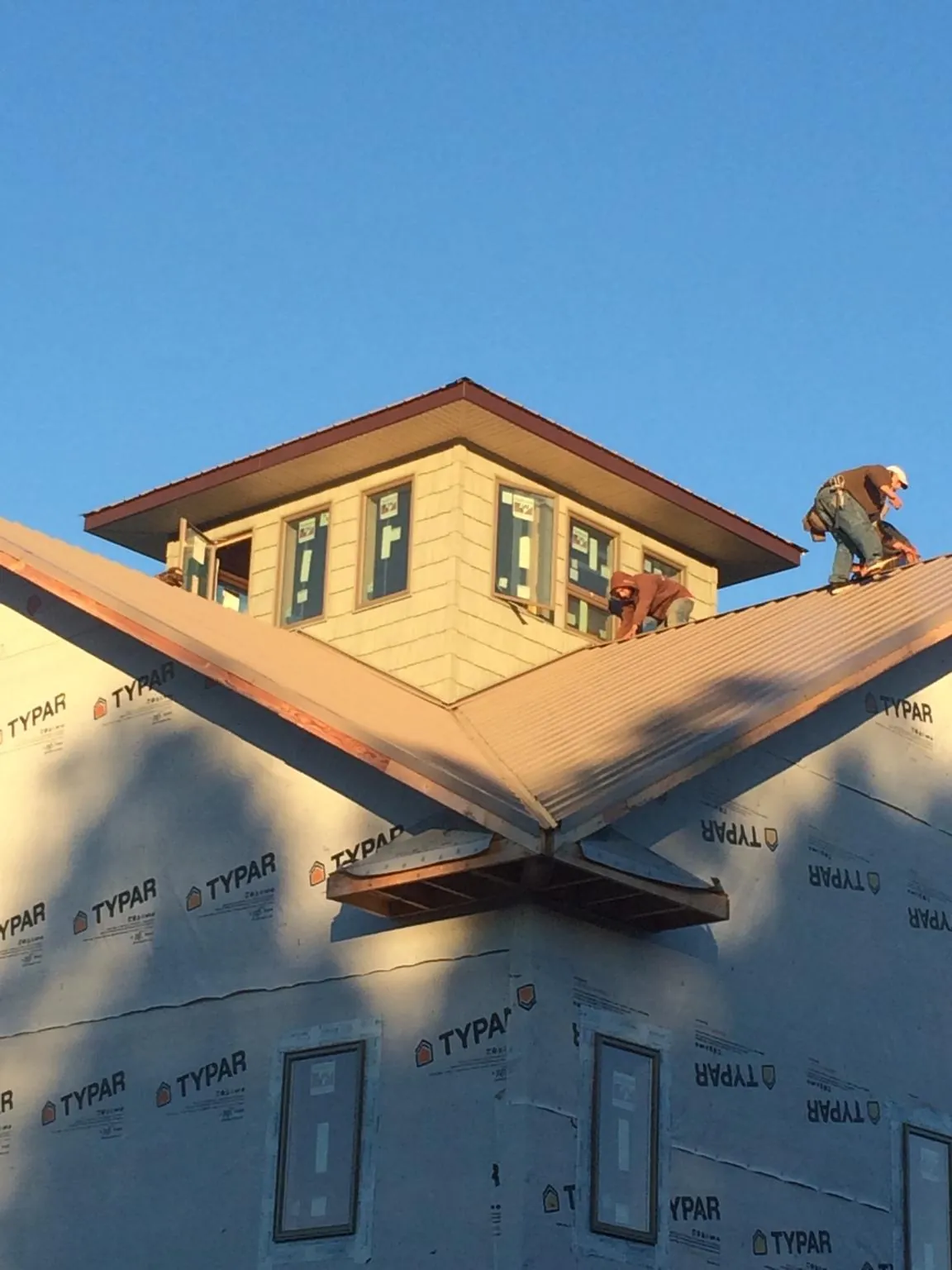 Roofers working around a rooftop cupola on a new metal roof at sunset — Roof Waterproofing in Payette by Roofing Brothers